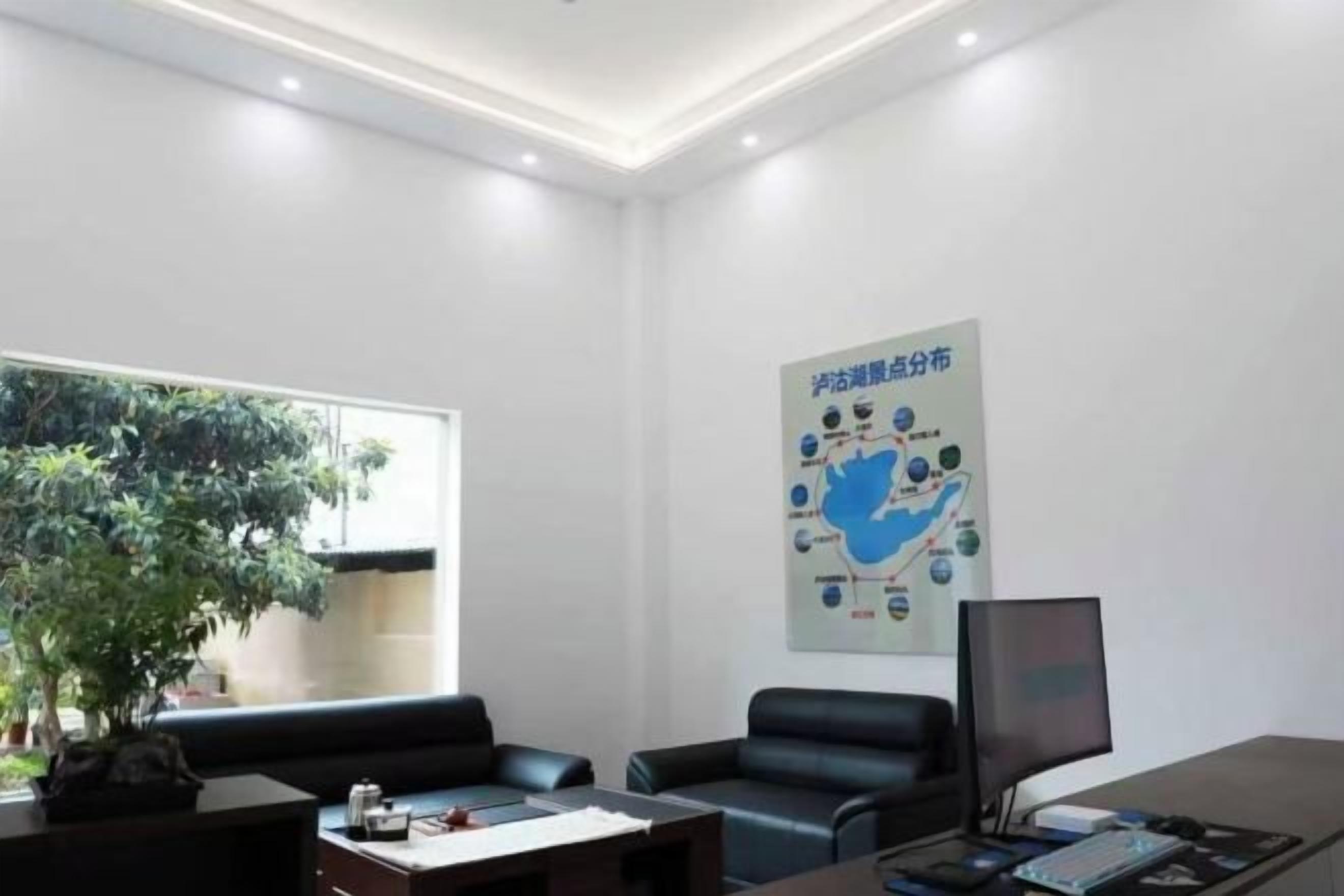 A modern office with a desk, two chairs, a computer, and a large window.