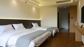 A hotel room with two beds, a wooden floor, a reception desk, and a television. - Lugu Lake Yongzhen Hotel (Ninglang)
