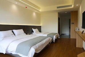 Ein Hotelzimmer mit zwei Betten, Holzboden, einer Rezeption und einem Fernseher.