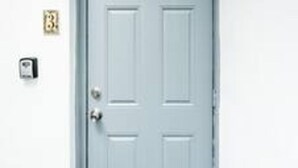 A white door with a silver handle and a keyhole. There is a small, square-shaped object mounted on the wall to the left of the door. - Zebra House Oasis, Ultimate Ft. Lauderdale Studio (Oakland Park)