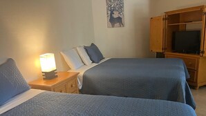 A hotel room with two beds, a nightstand with a lamp, a TV cabinet, and a wall art of a deer. - Relaxed And Spacious Studio 2343
 (Hallandale Beach)