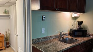 A kitchen with granite countertops, a stainless steel sink, a coffee maker, and a microwave. - Relaxed And Spacious Studio 2343
 (Hallandale Beach)