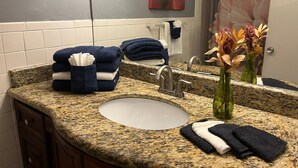 A bathroom with a granite countertop, a sink, a mirror, and towels. - Relaxed And Spacious Studio 2343
 (Hallandale Beach)