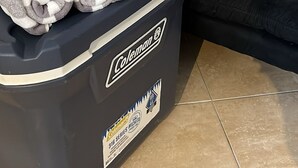 A storage bin with folded towels and a decorative pillow on a black couch. - Relaxed And Spacious Studio 2343
 (Hallandale Beach)