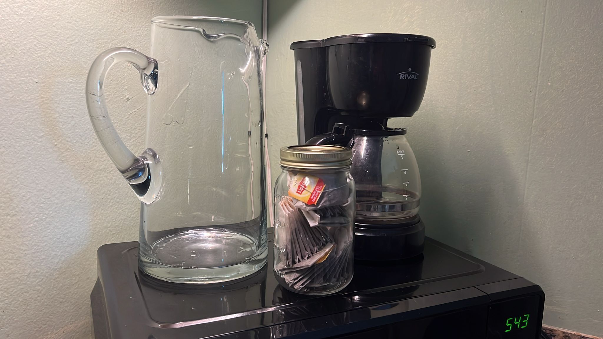 Un comptoir de cuisine avec un pichet en verre, une machine à café et un bocal de thé Lipton.