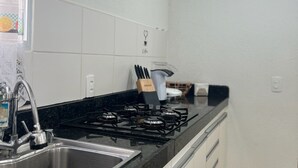 A modern kitchen with a gas stove, stainless steel sink, and a built-in range hood.