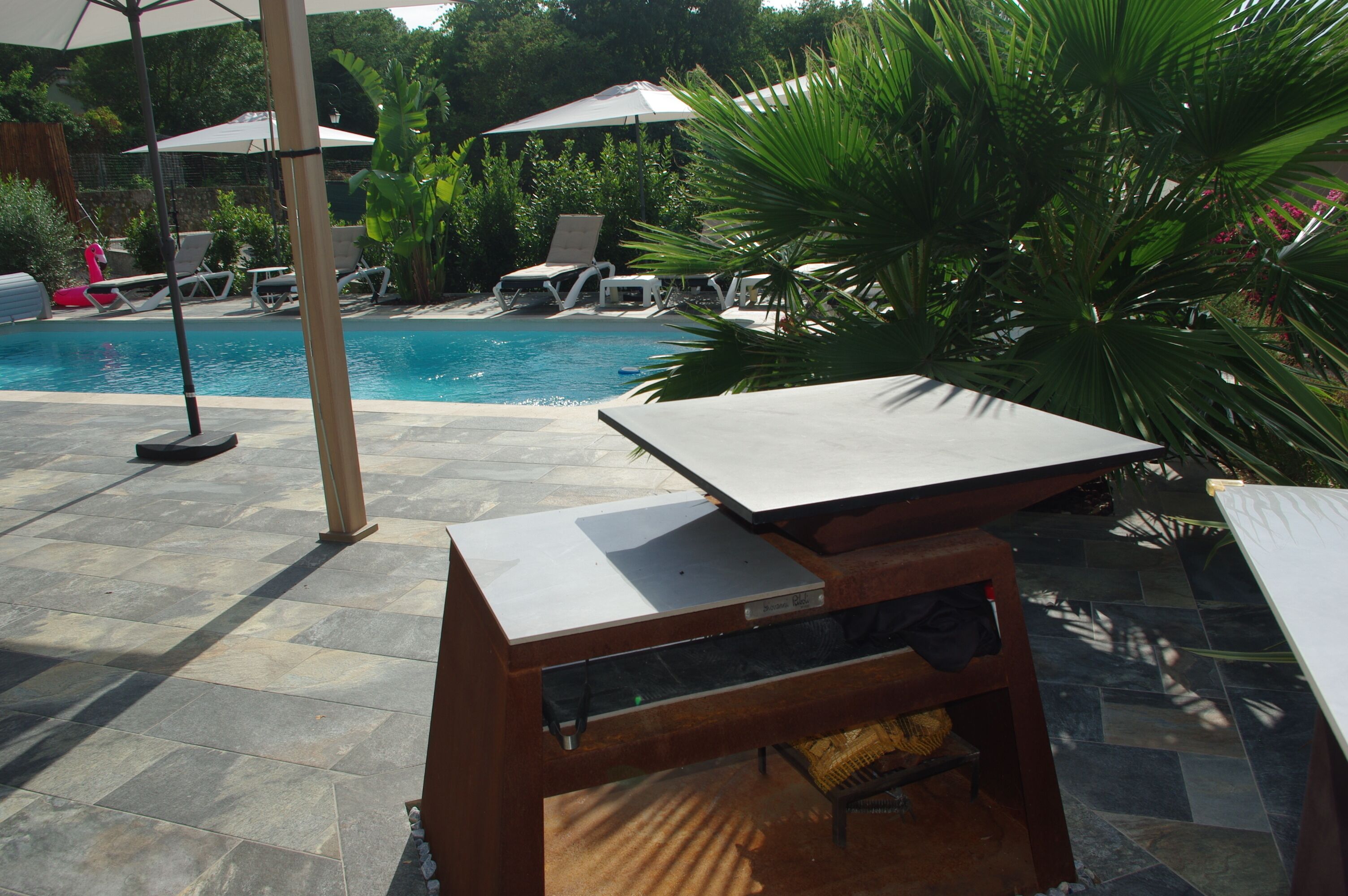 A poolside area with lounge chairs, umbrellas, and a small table.