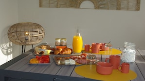 Une table de petit-déjeuner avec des croissants, des fruits, des œufs et des boissons.