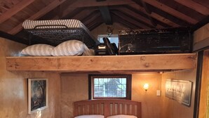 A rustic wooden room with a bunk bed, a framed picture on the wall, and a window with a view. - The Overleigh Shearers Quarters (Port Levy)