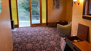 A room with a patterned carpet, a wooden bench, a table, and a painting on the wall. - The Overleigh Shearers Quarters (Port Levy)