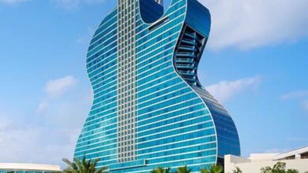 Ein modernes Gebäude mit einem einzigartigen, gitarrenförmigen Design, das durch horizontale Linien und ein zentrales vertikales Element gekennzeichnet ist.