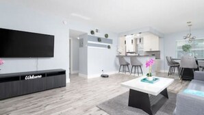 A modern living room with a flat-screen TV, a coffee table, and a sofa. - Stylish Vacation home Coral Ridge (Oakland Park)
