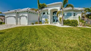 A two-story house with a white exterior, a garage, and a well-maintained lawn.