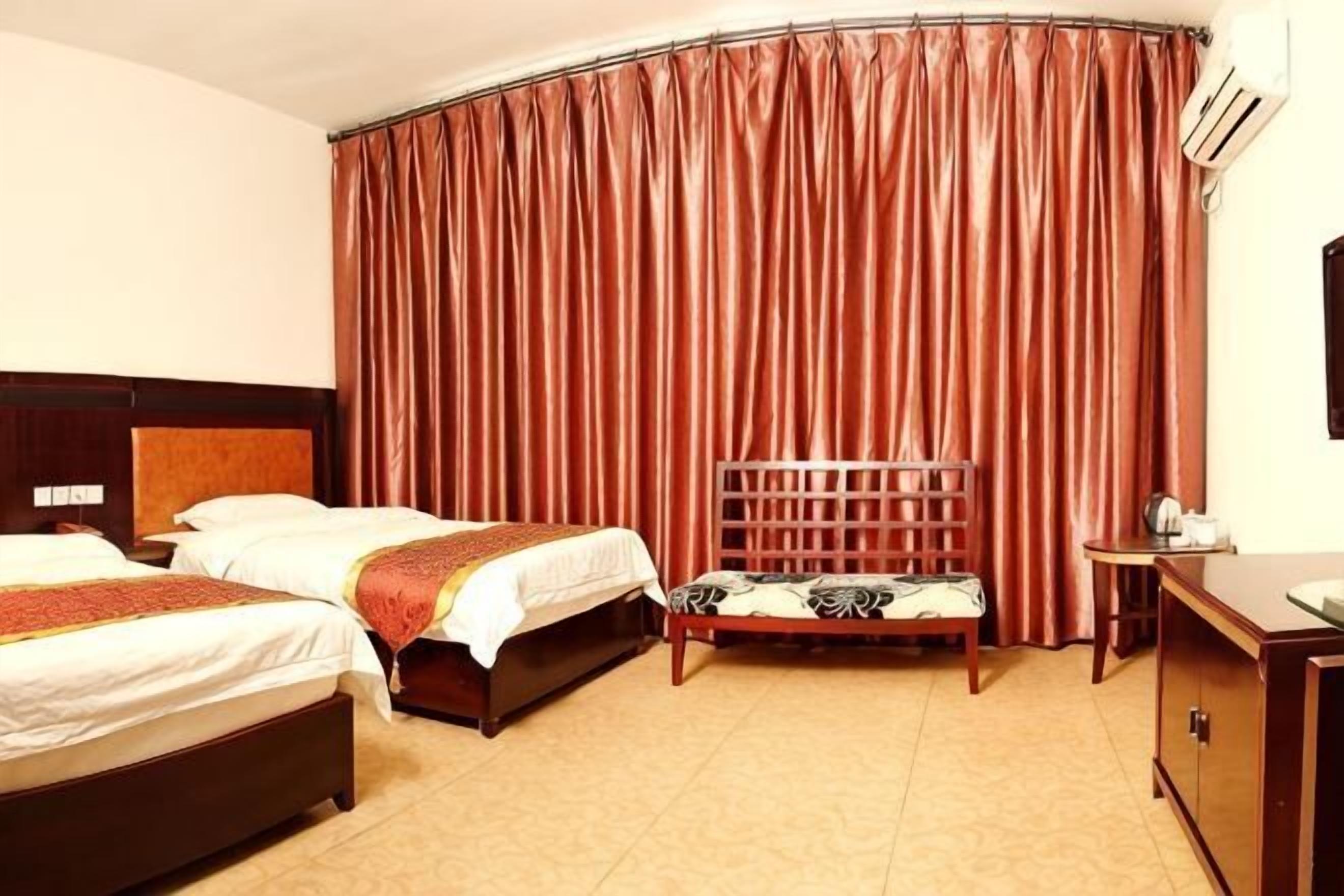 A hotel room with two beds, a wooden headboard, a desk, and a chair.