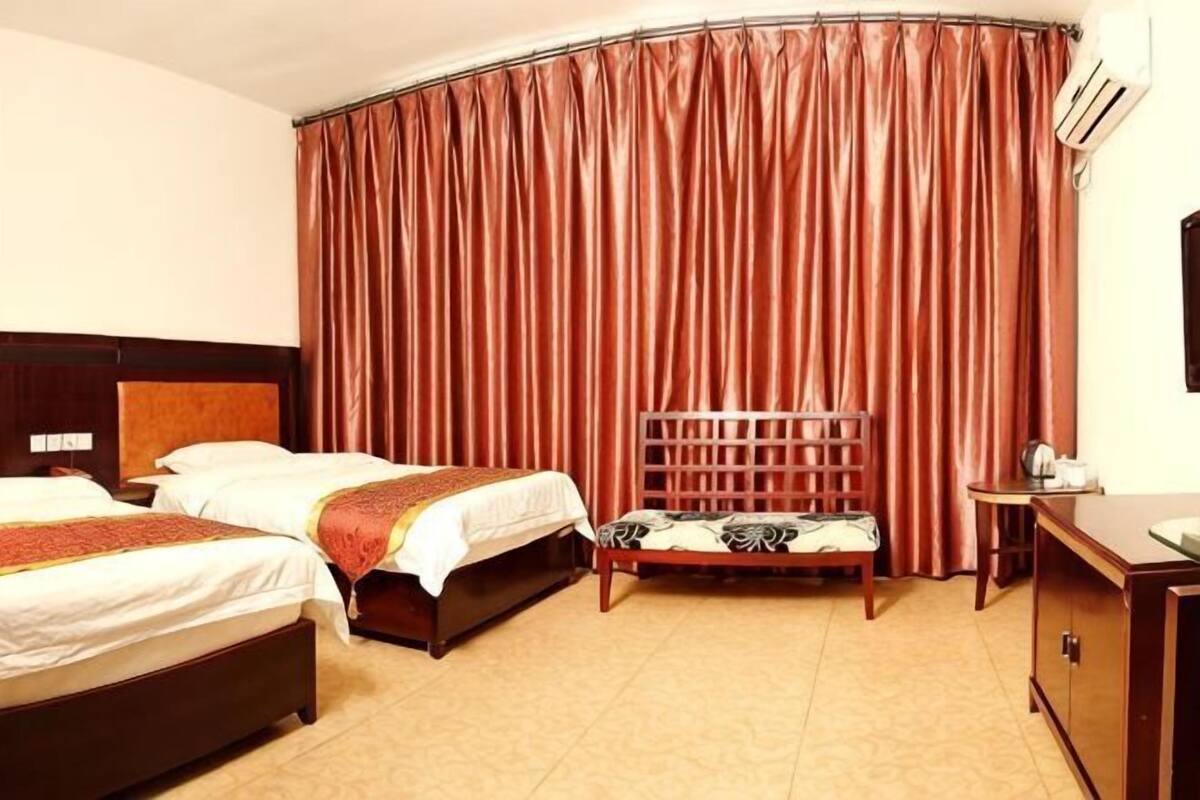 A hotel room with two beds, a wooden headboard, a desk, and a chair.