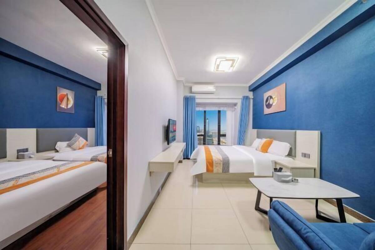 Habitació d'hotel amb dos llits, una taula petita, un sofà i una televisió.