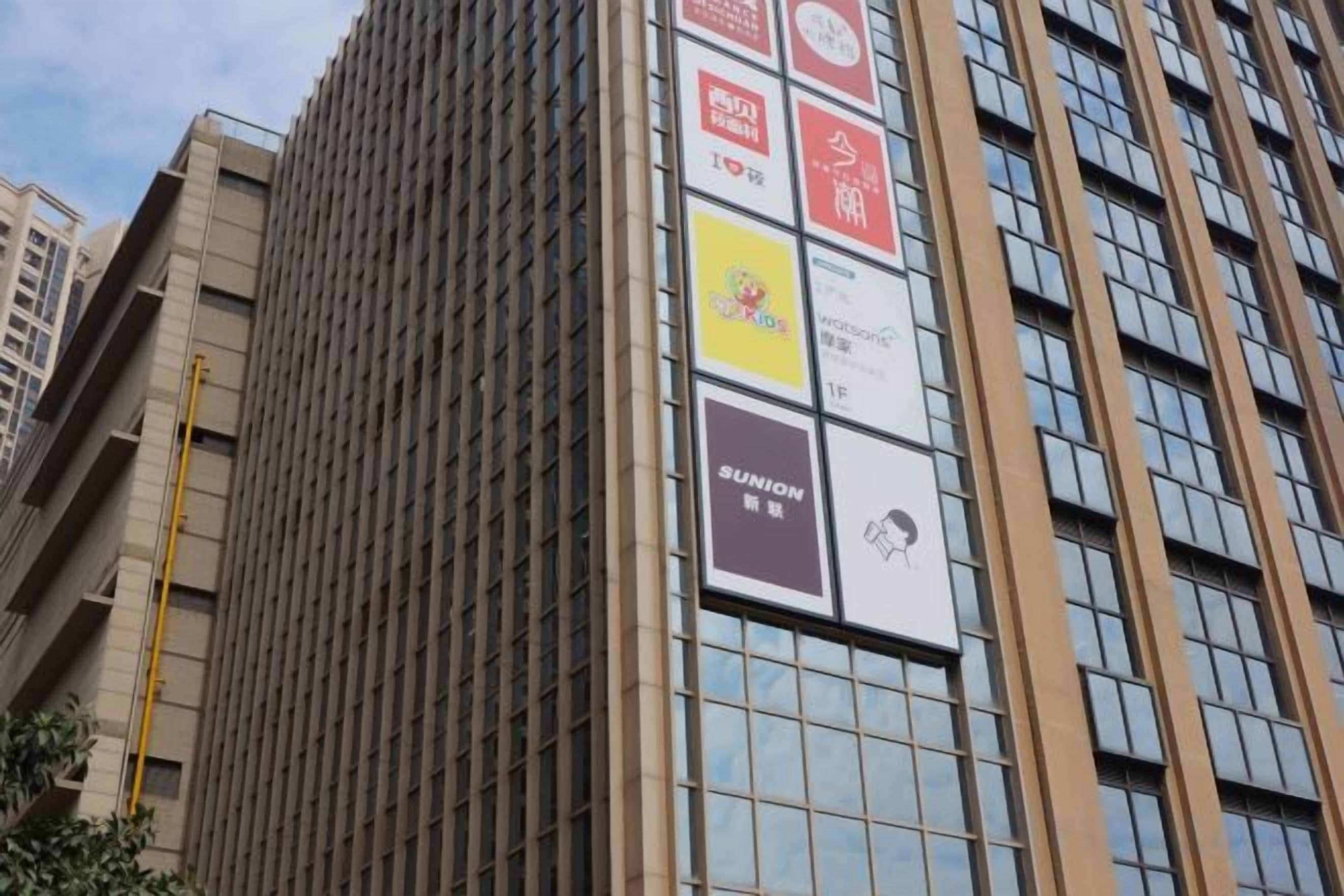 A tall building with multiple windows and several advertisements.