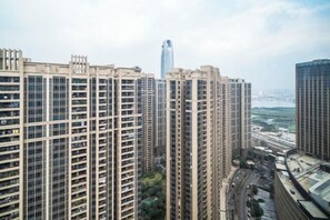 A high-rise residential building with multiple balconies, a central elevator shaft, and a view of a cityscape in the background. - Angda Pazhou Apartment (Guangzhou Pazhou International Exhibition Center) (Guangzhou)