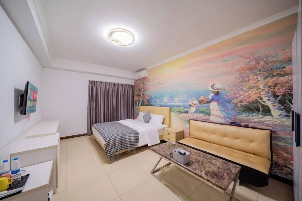Una habitació d'hotel amb un llit, un sofà, un escriptori i un quadre a la paret.