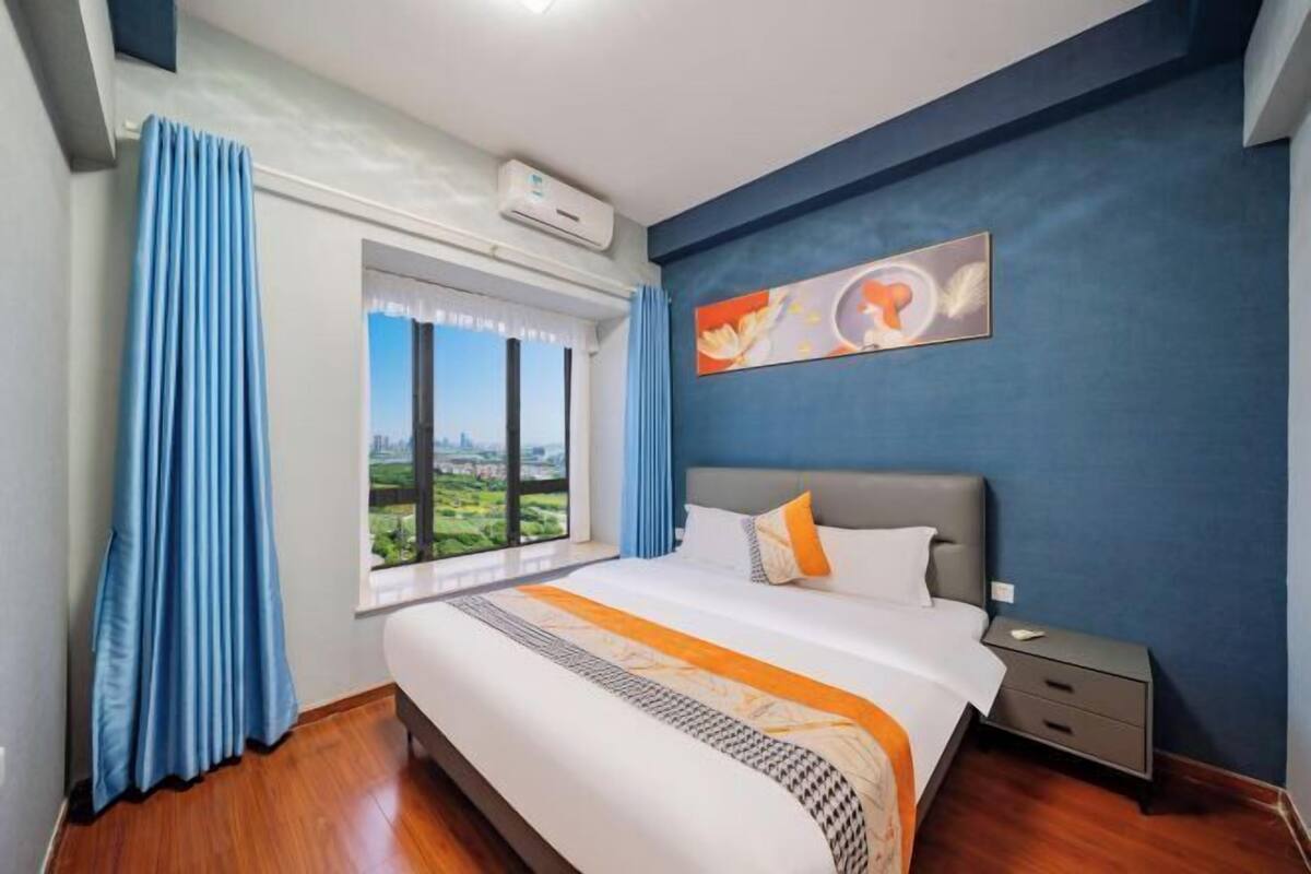 Habitació d'hotel amb un llit gran, una tauleta de nit, una finestra amb cortines i un quadre a la paret.