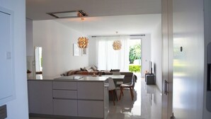 Cozinha moderna com ilha central, área de refeições com cadeiras e uma grande janela que oferece luz natural.