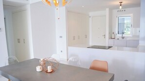 Cozinha moderna com armários brancos, uma ilha central e um espaço de refeições com mesa e cadeiras.