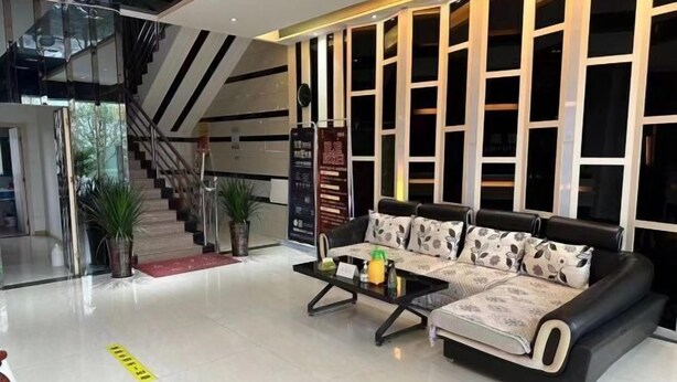 A modern lobby with a black leather sofa, a glass staircase, and a wall with vertical windows.