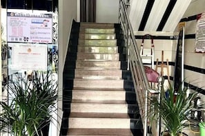 A staircase with handrails, surrounded by potted plants, and signs on the walls. - Ruijun Laikehao Hotel Jingzhou (Jingzhou)
