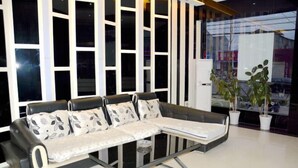 A modern living room with a sectional sofa, a glass coffee table, and potted plants.