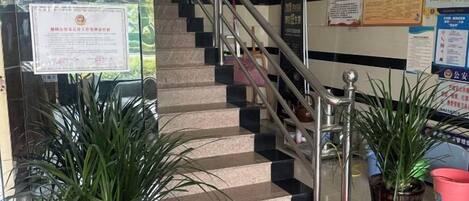 A staircase with handrails, potted plants, and informational posters.