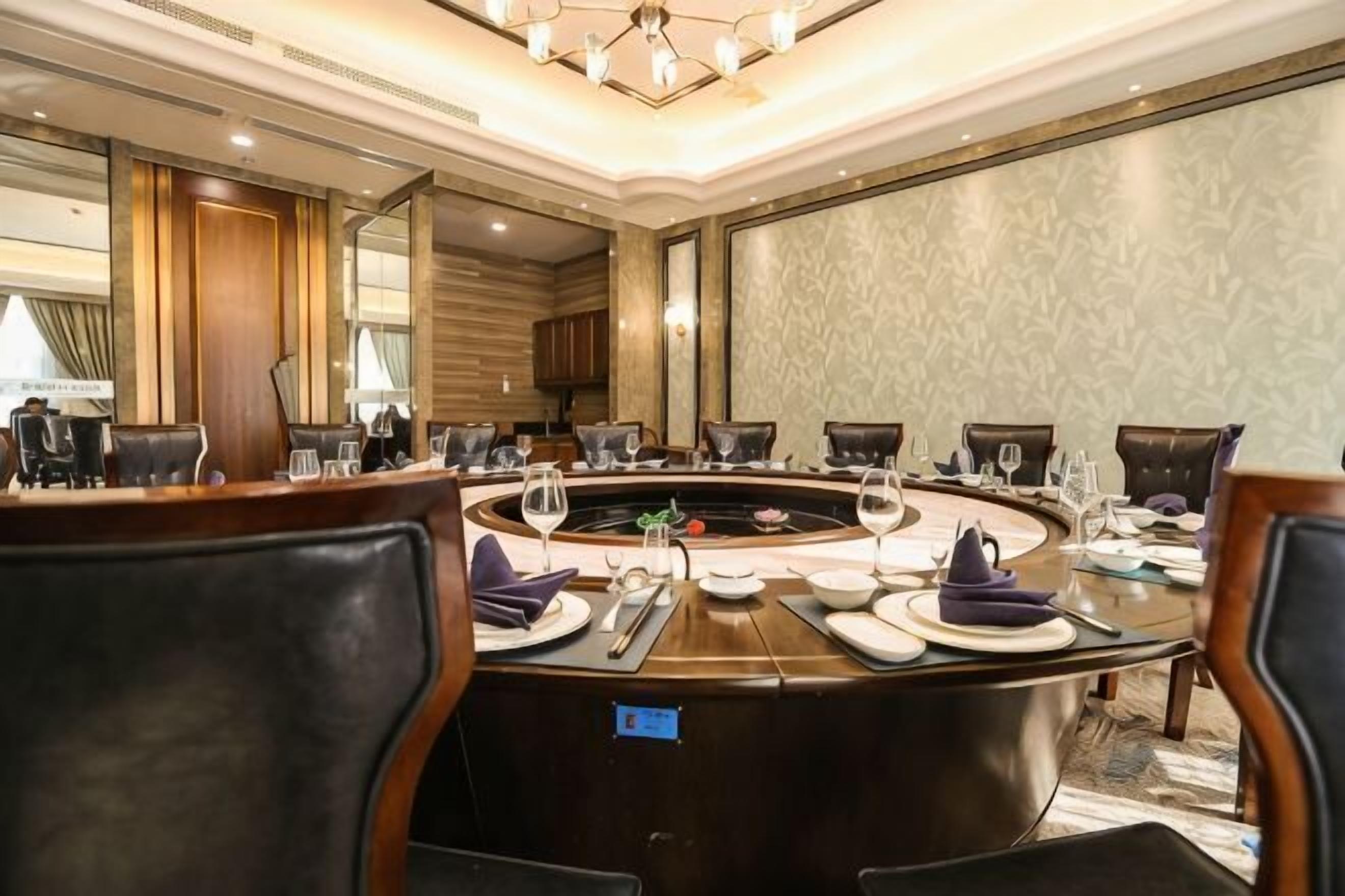 A conference room with a round table, chairs, and a large mirror.