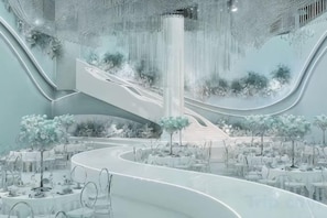 Un intérieur moderne avec un escalier en colimaçon central, des plantes d’intérieur et des tables disposées autour d’une allée centrale.