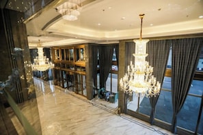 Eine großzügige Lobby mit Kronleuchtern, großen Fenstern und einem spiegelnden Boden.