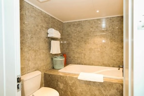 Une salle de bain avec des toilettes, une baignoire et un mur en marbre.