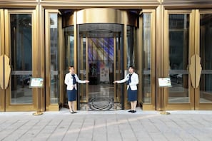 L'entrée d'un hôtel, avec des portes tournantes et un panneau indicateur.