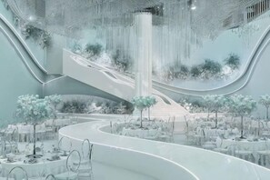 Un interno moderno con una scala a chiocciola centrale, piante da interno e tavoli apparecchiati per la cena.