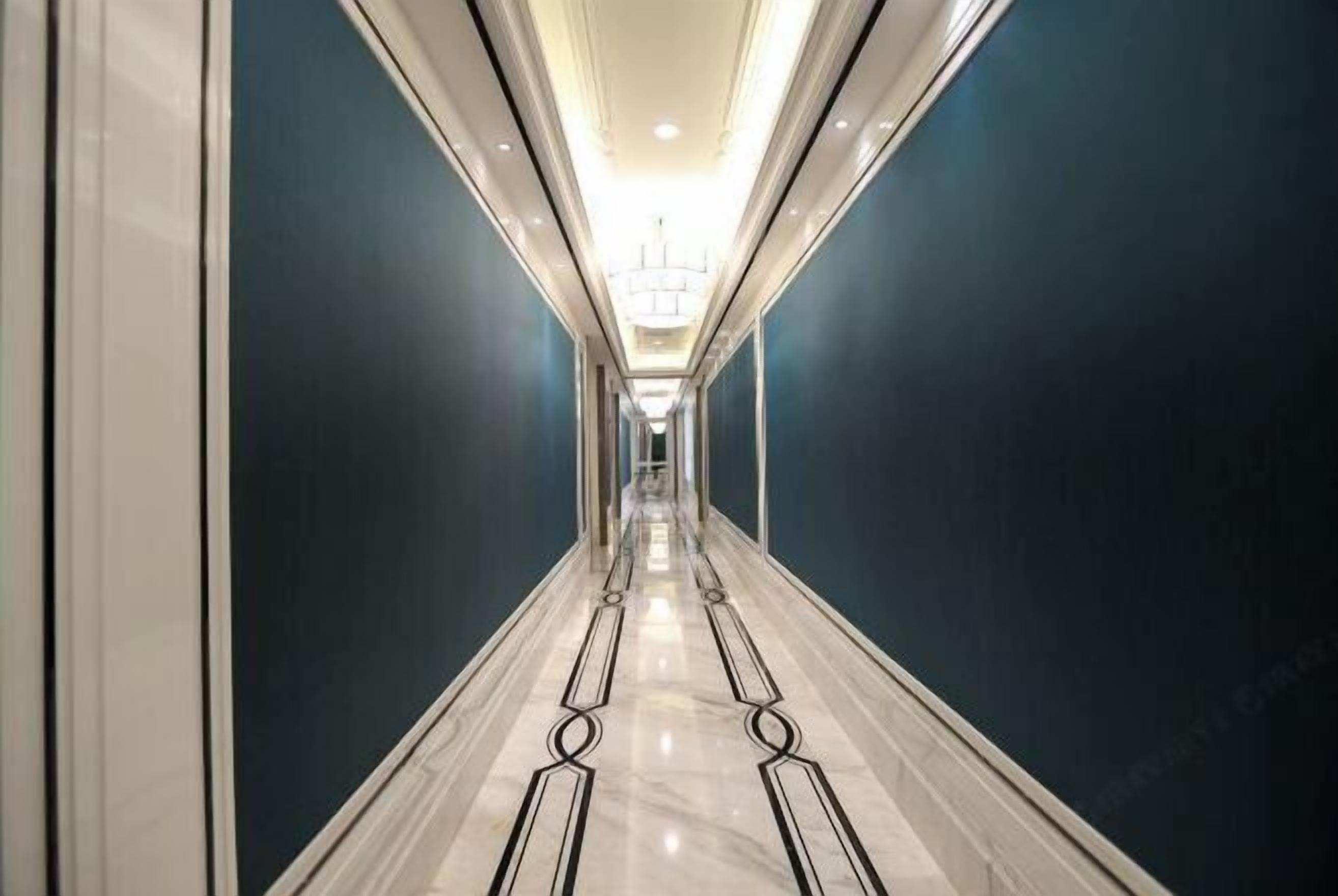 A long, narrow hallway with dark blue walls and a shiny, reflective floor.