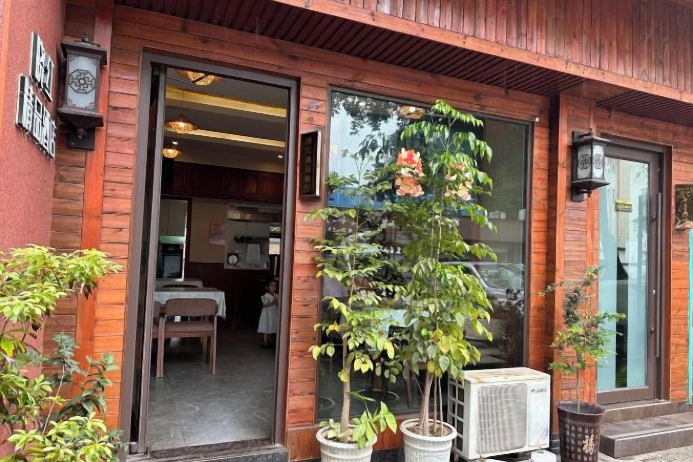 A building entrance with a wooden facade, a glass door, and a potted plant outside.