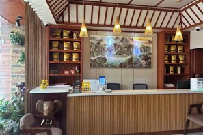 Un comptoir d’accueil avec un revêtement en bois, une grande peinture au-dessus et une étagère contenant divers objets.