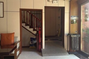 Eine Hotelhalle mit Treppe, einer Rezeption und einem Mülleimer.