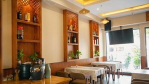 Un restaurante con estantes de madera, mesas, sillas y una pantalla de televisión.