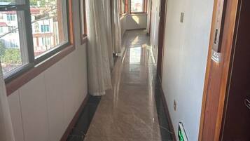 A corridor with a tiled floor, a door on the right, and a window on the left.
