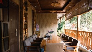 Un comedor de madera con una mesa larga y varias sillas, rodeado de paredes de madera y un balcón con barandilla.