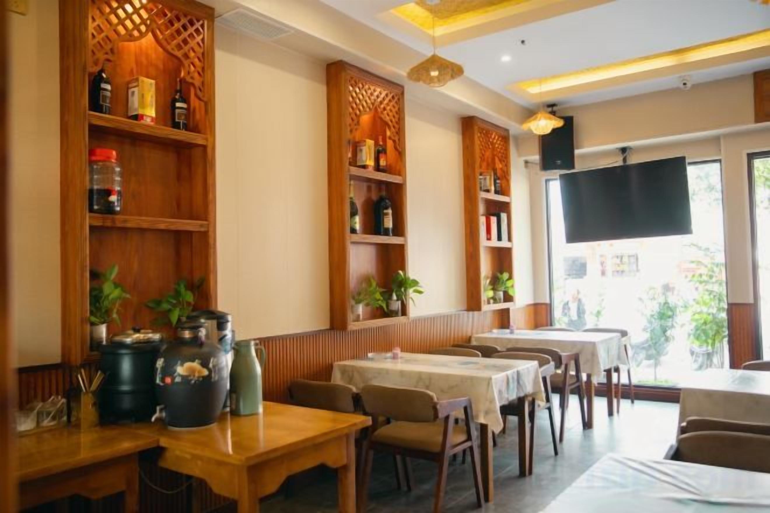 Ein Restaurantinneres mit Holzböden, Tischen, Stühlen und einem großen Fernsehbildschirm.