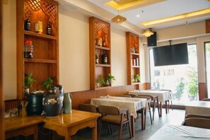 Ein Restaurantinneres mit Holzböden, Tischen, Stühlen und einem großen Fernsehbildschirm.
