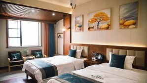 Habitación de hotel con dos camas, un ventanal grande y obras de arte en las paredes.