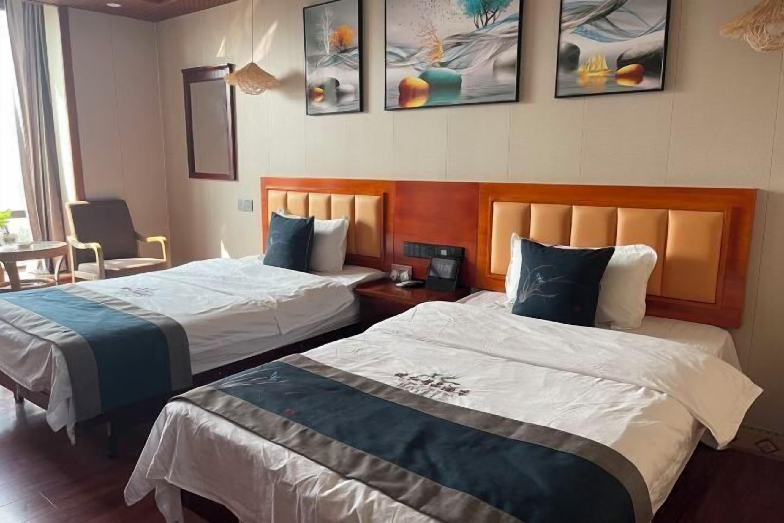 Habitación de hotel con dos camas, cabecero de madera, una silla y una obra de arte en la pared.