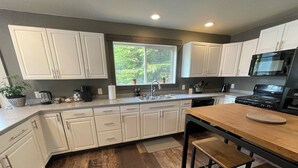 A modern kitchen with white cabinets, a wooden countertop, and a built-in stove. - Cozy Getaway in Mullan (Mullan)