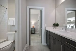 Un baño moderno con inodoro, lavamanos y espejo.