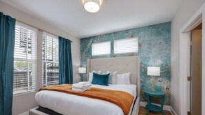 Een moderne slaapkamer met een groot bed, twee bedlampjes en uitzicht op de stad door de ramen.